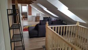 A loft-style room with a wooden staircase, a sofa, and a multi-tiered shelving unit. - Dresdner-Tag Hermann (Dresden)