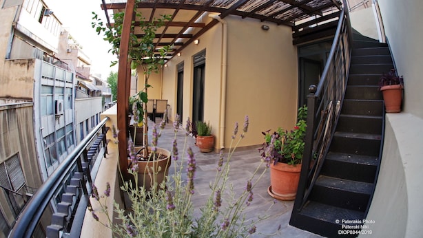 A covered outdoor area with a staircase, potted plants, and a metal railing.