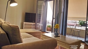 A living room with a sofa, a coffee table with a vase, a lamp, and a TV on a stand.