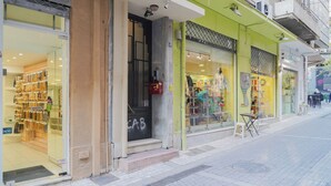 Un escaparate con puerta de cristal, un letrero visible y un pequeño área de asientos al aire libre.