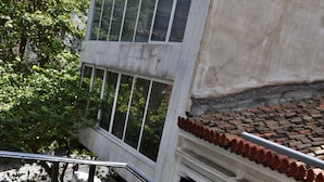 A wooden table with a bouquet of red roses, two wine glasses, and two bottles of water on a balcony with a metal railing.
