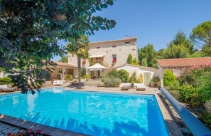 A swimming pool with lounge chairs and umbrellas, surrounded by greenery and a stone building with a tiled roof. - Vacation home in the Pays de Cocagne, in a quiet location with a large swimming pool (Aguts)