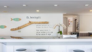 Une cuisine moderne dotée d’un coin bar, de meubles blancs et d’un mur décoratif orné d’illustrations de poissons et d’une citation.