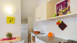A kitchen with a sink, stove, cabinets, and a dining area with a chair and table. - Studio near the beach - Apartment Lucia (Campo nell'Elba)