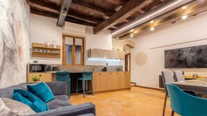 A modern kitchen with a central island, a dining area with a table and chairs, and a living area with a sofa. - Suite Italy Roma - Luxury apartment in the heart of Rome (Roma)