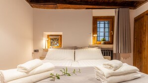 A hotel room with a bed, towels, a window with curtains, and a wooden ceiling. - Suite Italy Roma - Luxury apartment in the heart of Rome (Roma)