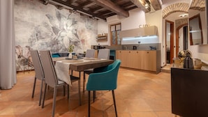 A dining area with a table, chairs, and a mural on the wall. - Suite Italy Roma - Luxury apartment in the heart of Rome (Roma)