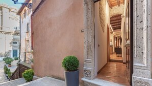 A building entrance with a potted plant, a tiled pathway, and a doorway leading to an interior space. - Suite Italy Roma - Luxury apartment in the heart of Rome (Roma)