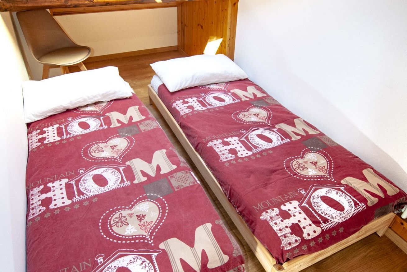Two twin beds with matching bedding in a room with wooden walls and a chair.