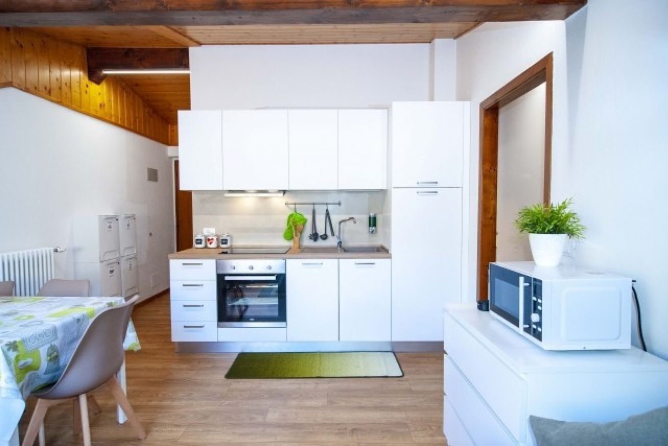 A compact kitchen with white cabinets, a microwave, and a small dining area with a table and chairs.