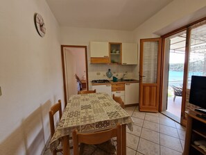 Une cuisine de taille réduite comprenant une table à manger, des chaises et un meuble pour la télévision.
