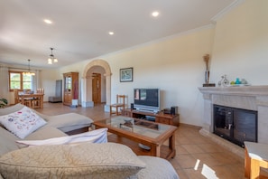 A living room with a sofa, TV, fireplace, and a dining area with a table and chairs.