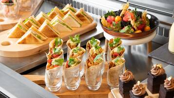 Un bufé con diversas opciones de comida, incluyendo sándwiches, wraps y postres.