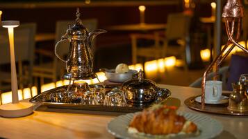 A table set with a teapot, cups, a tray, and a plate with a pastry.