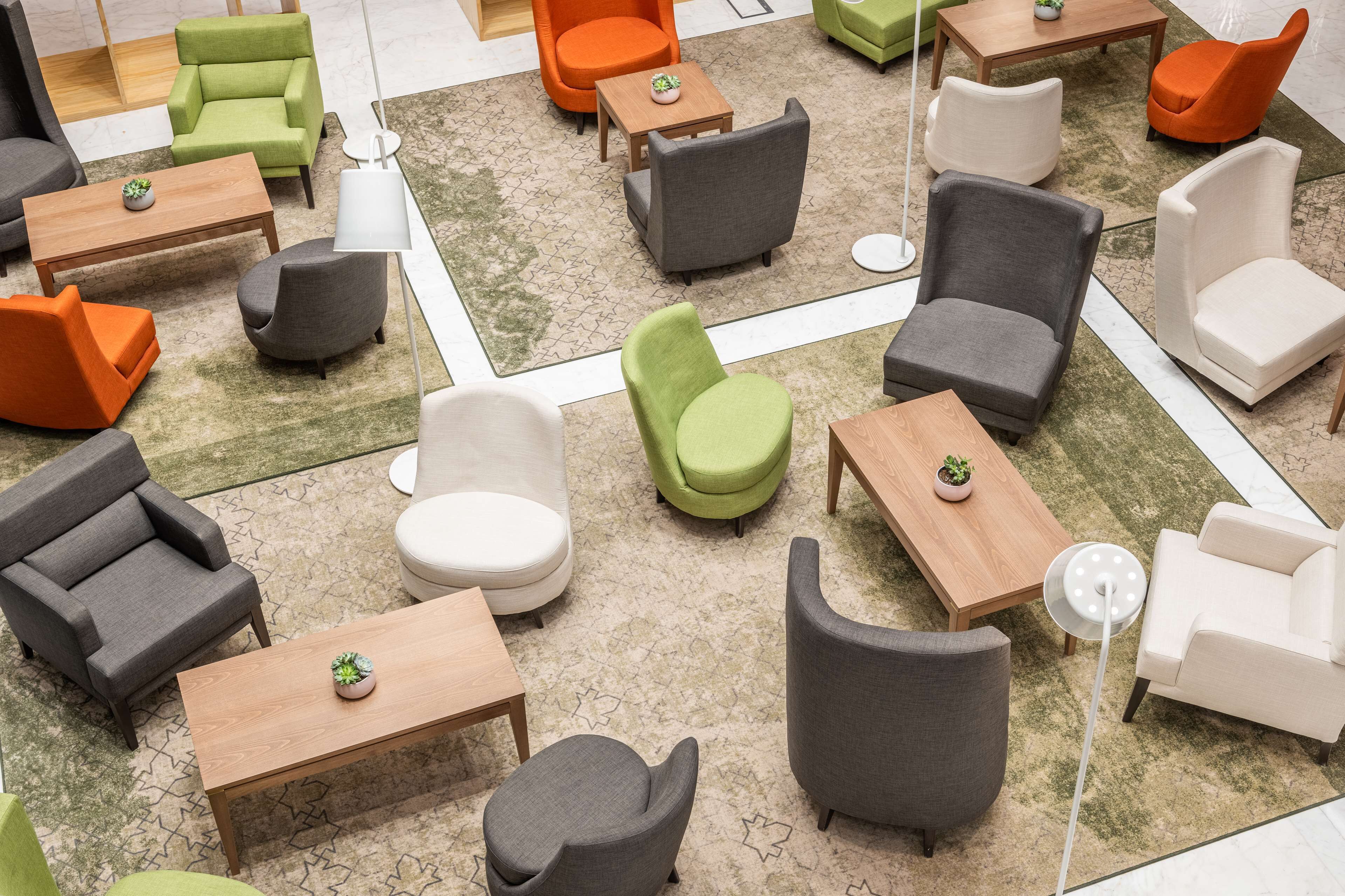 A modern indoor seating area with various sofas and chairs arranged around tables, featuring a mix of colors and textures.