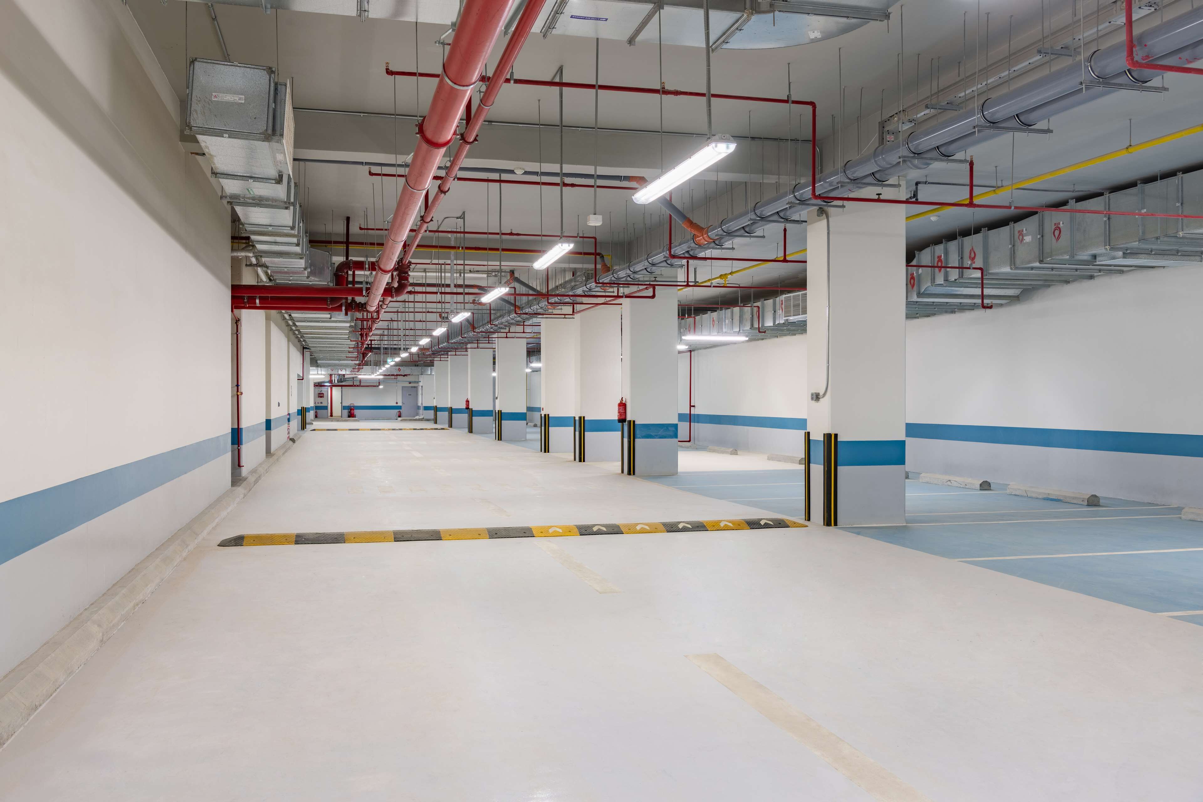 A spacious, well-lit indoor area with a long corridor lined with columns and fire safety equipment.
