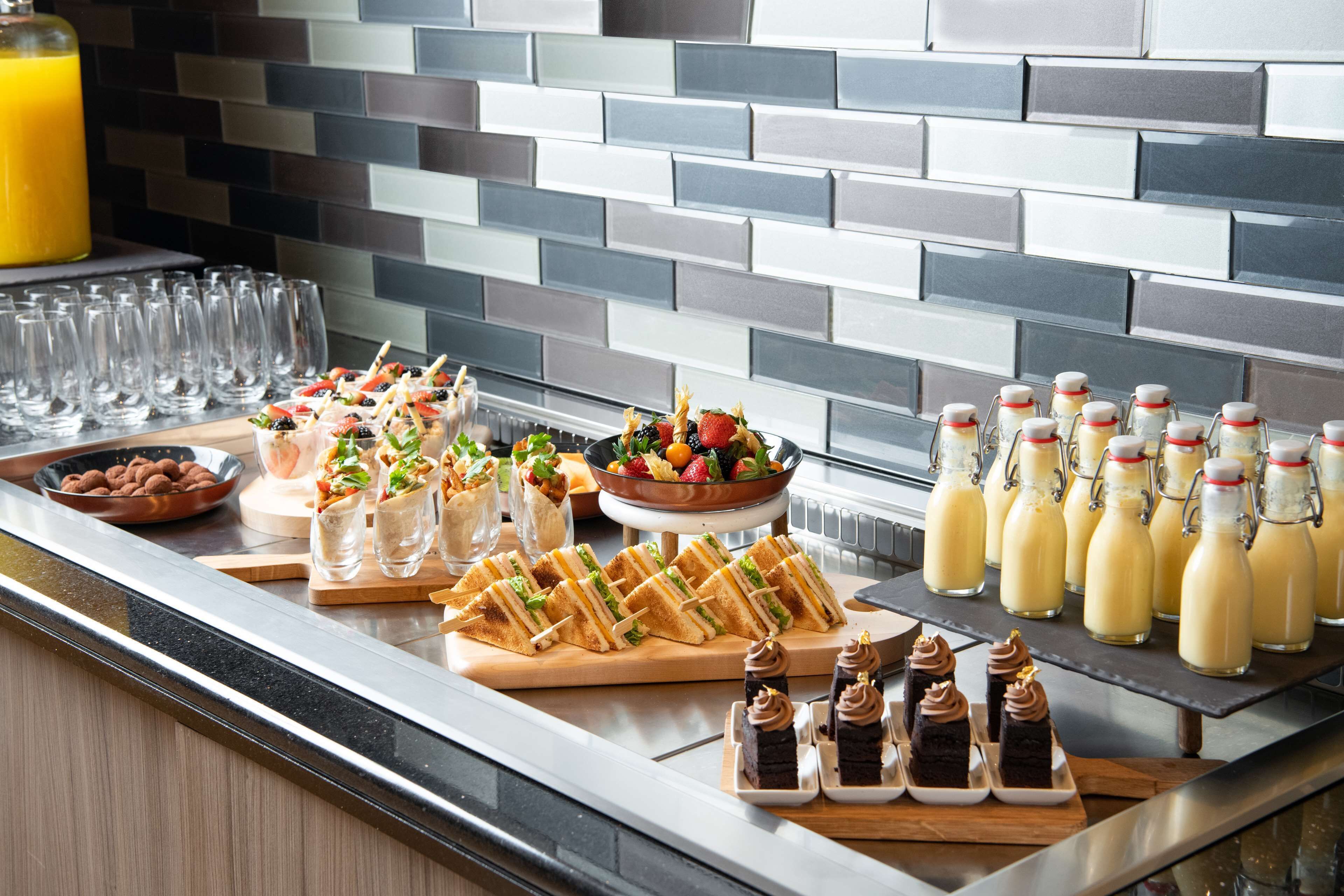 A buffet with various food items and beverages, including sandwiches, salads, and milkshakes.