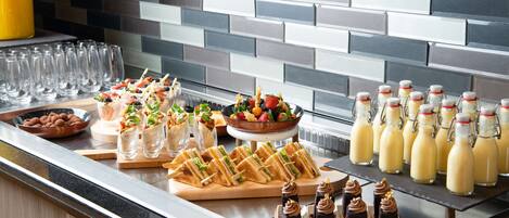 A buffet with various food items and beverages, including sandwiches, salads, and milkshakes.