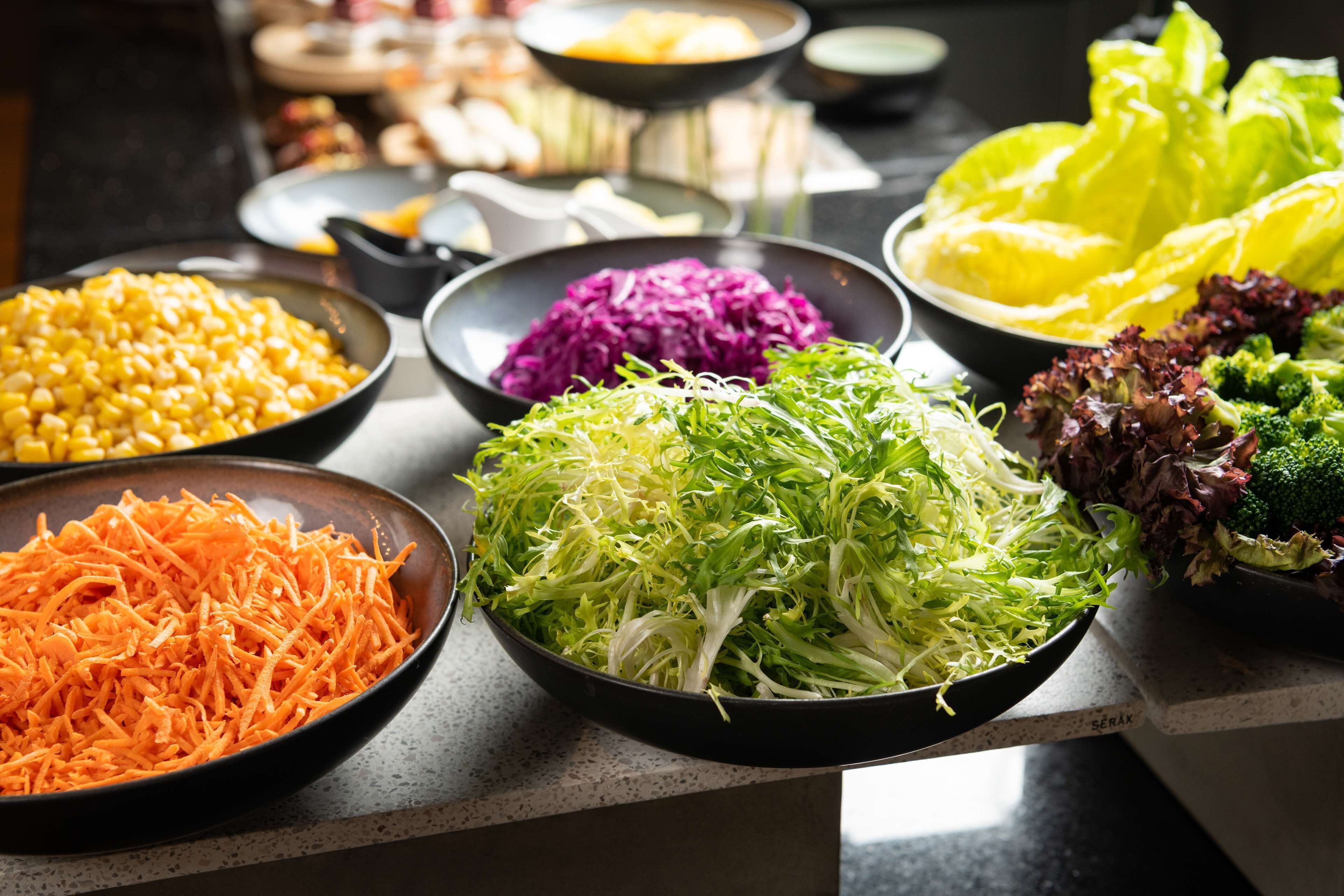 A variety of fresh vegetables including carrots, purple cabbage, and broccoli on a kitchen counter.