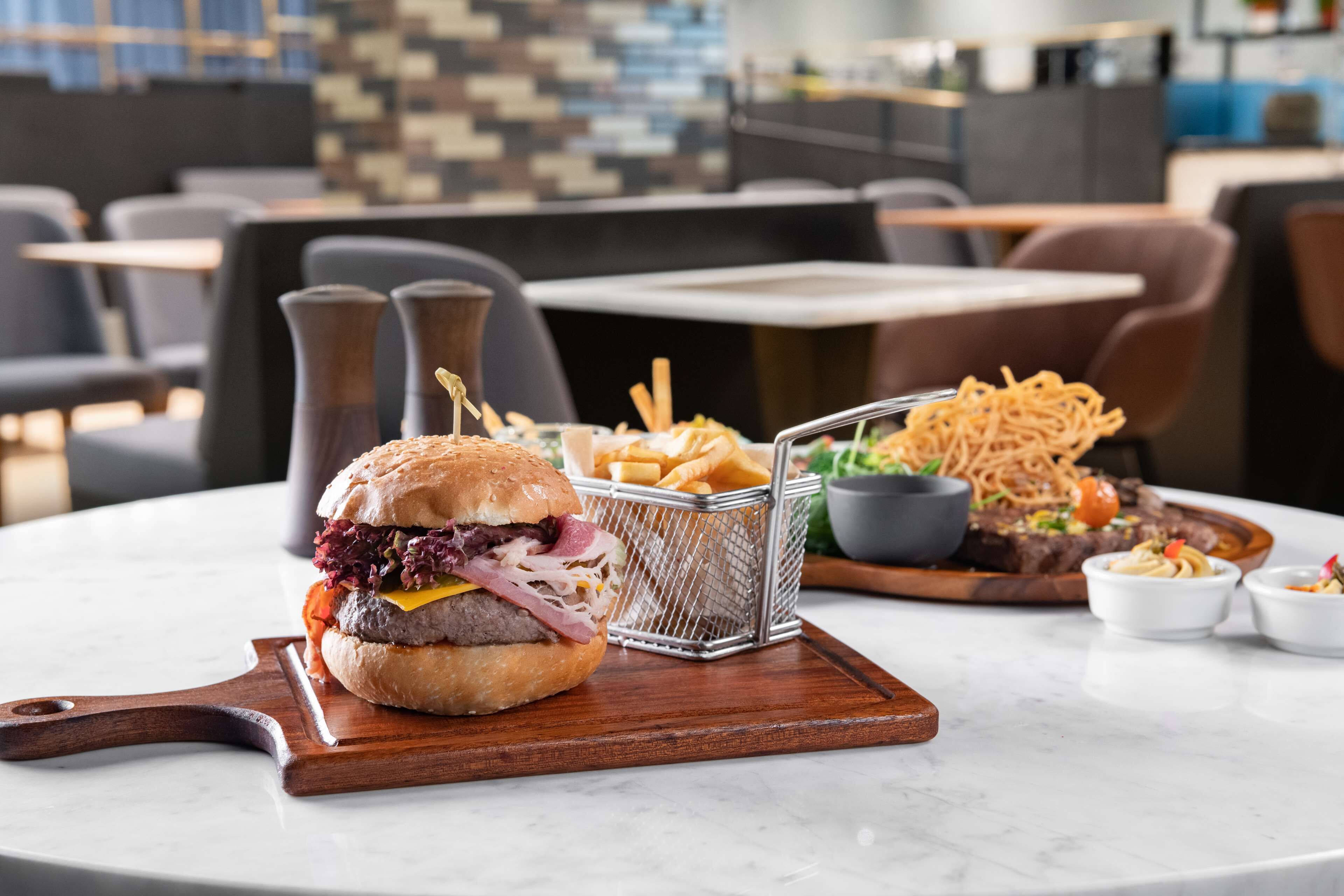 A dining table with a burger, fries, and a salad.