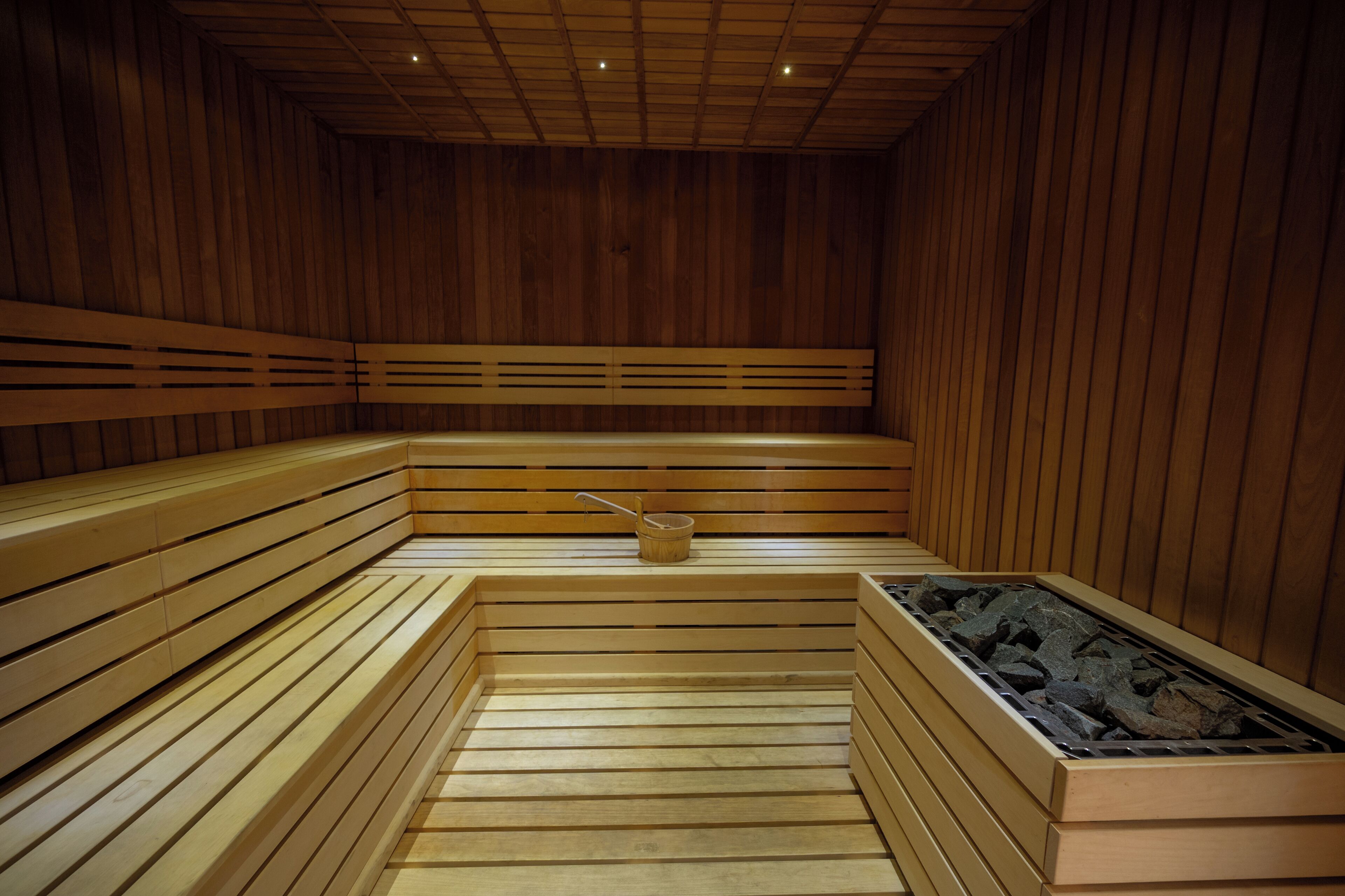 Una sauna con bancos de madera y una cuenca de piedra.