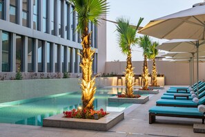 A rooftop pool area with lounge chairs, palm trees, and a modern building in the background. - Park Inn by Radisson, Riyadh (Riyadh)