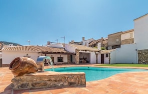 Una piscina amb una font, envoltada d'edificis tradicionals amb teulades de rajola.