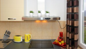 Uma cozinha com bancada, torradeira, chaleira, bloco de facas e cesta de frutas.
