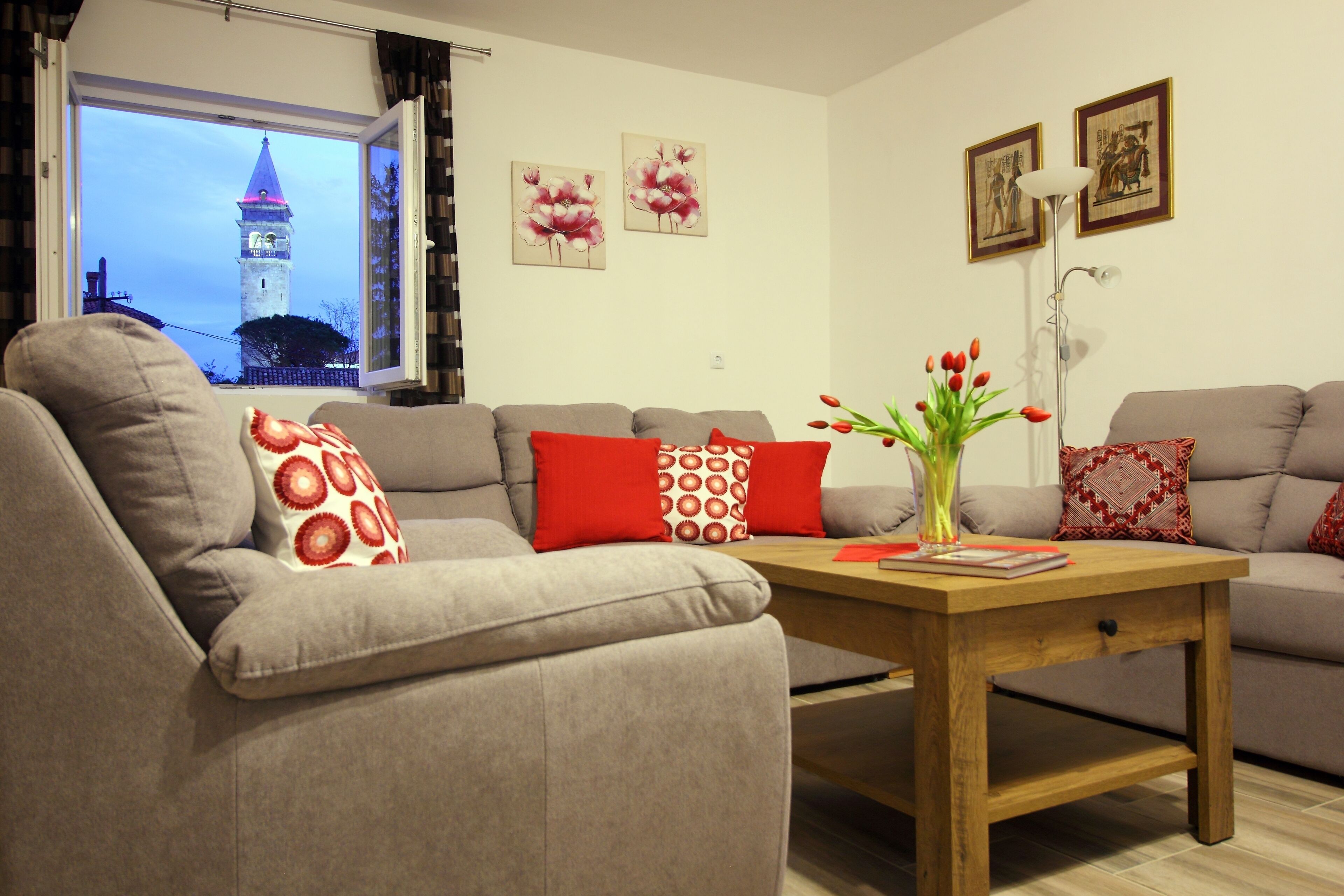 A living room with a sofa set, a wooden coffee table, and a window with a view of a tower.