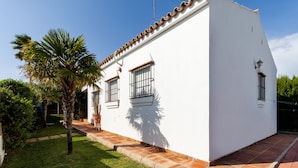 A white building with a tiled roof, a small garden with a palm tree, and a clear blue sky. - Holiday Home "La Buganvilla" For Families With Garden and Large Pool (Conil de la Frontera)