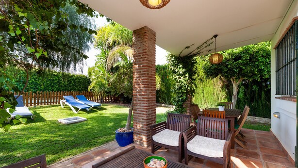 A patio with a brick pillar, wooden furniture, and a bowl of fruit. - Holiday Home "La Buganvilla" For Families With Garden and Large Pool (Conil de la Frontera)