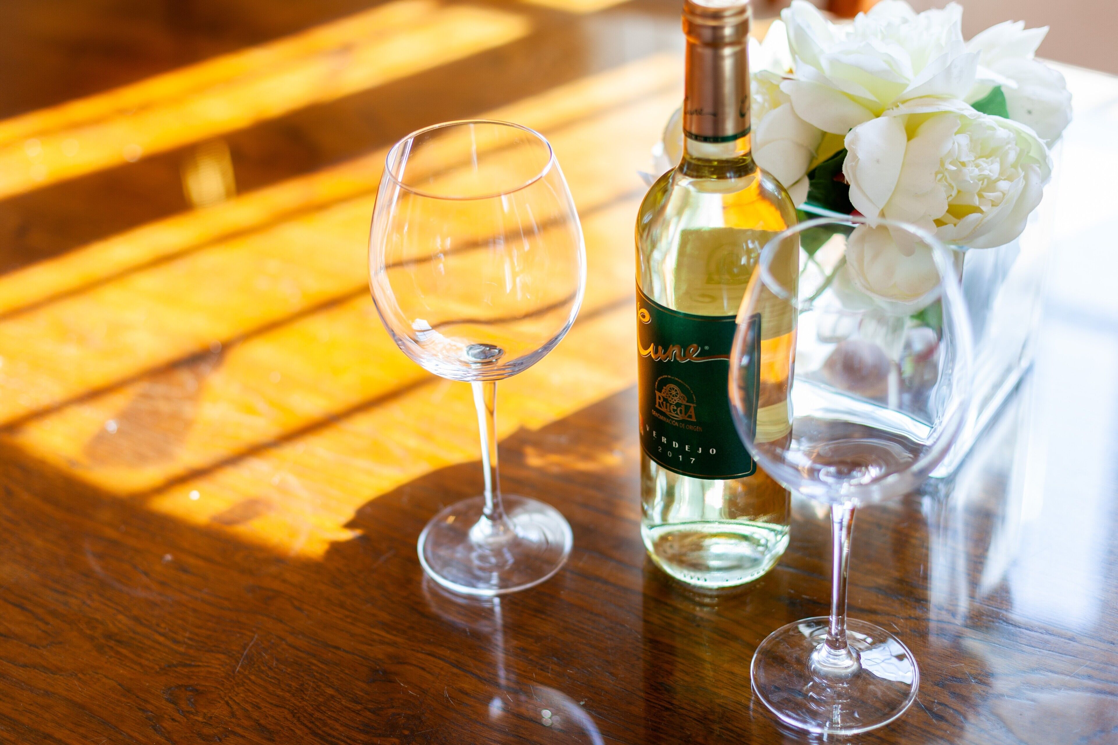 A wooden table with two wine glasses and a bottle of wine.