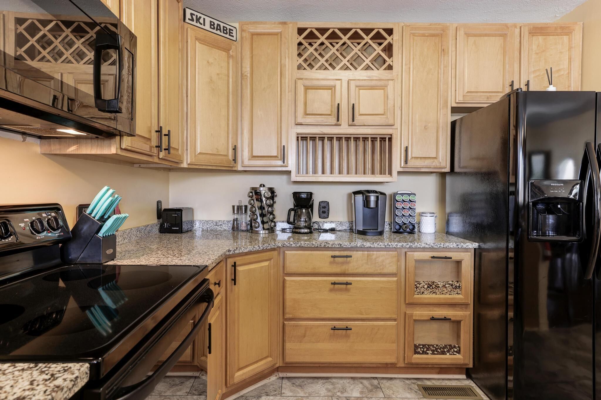 A kitchen with wooden cabinets, a black refrigerator, a stove, and various appliances.