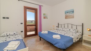 Slaapkamer met twee bedden, een raam met uitzicht, een deur en een aan de muur hangend schilderij.