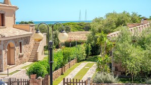 Een villa in mediterrane stijl met stenen architectuur, een tuin met een pad van stenen en uitzicht op zee.