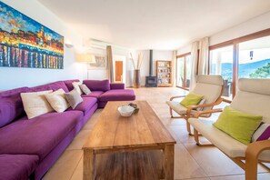 A living room with a purple sofa, a wooden coffee table, and a bookshelf.