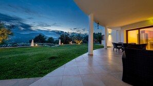 Eine moderne Außenpatio mit Blick auf die Berge, einer Rasenfläche und Gartenmöbeln.