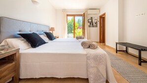 Ein Schlafzimmer mit zwei Betten, einer Bank, einer Tür und Blick ins Grüne.