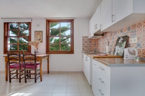 Eine Küche mit Esstisch, Stühlen, einem Fenster und einer gefliesten Spritzschutzwand.