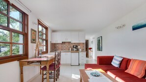 Ett kompakt bostadsutrymme med ett matområde, kök och en röd soffa.