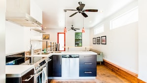 A modern kitchen with stainless steel appliances, a dishwasher, and a wooden floor.
