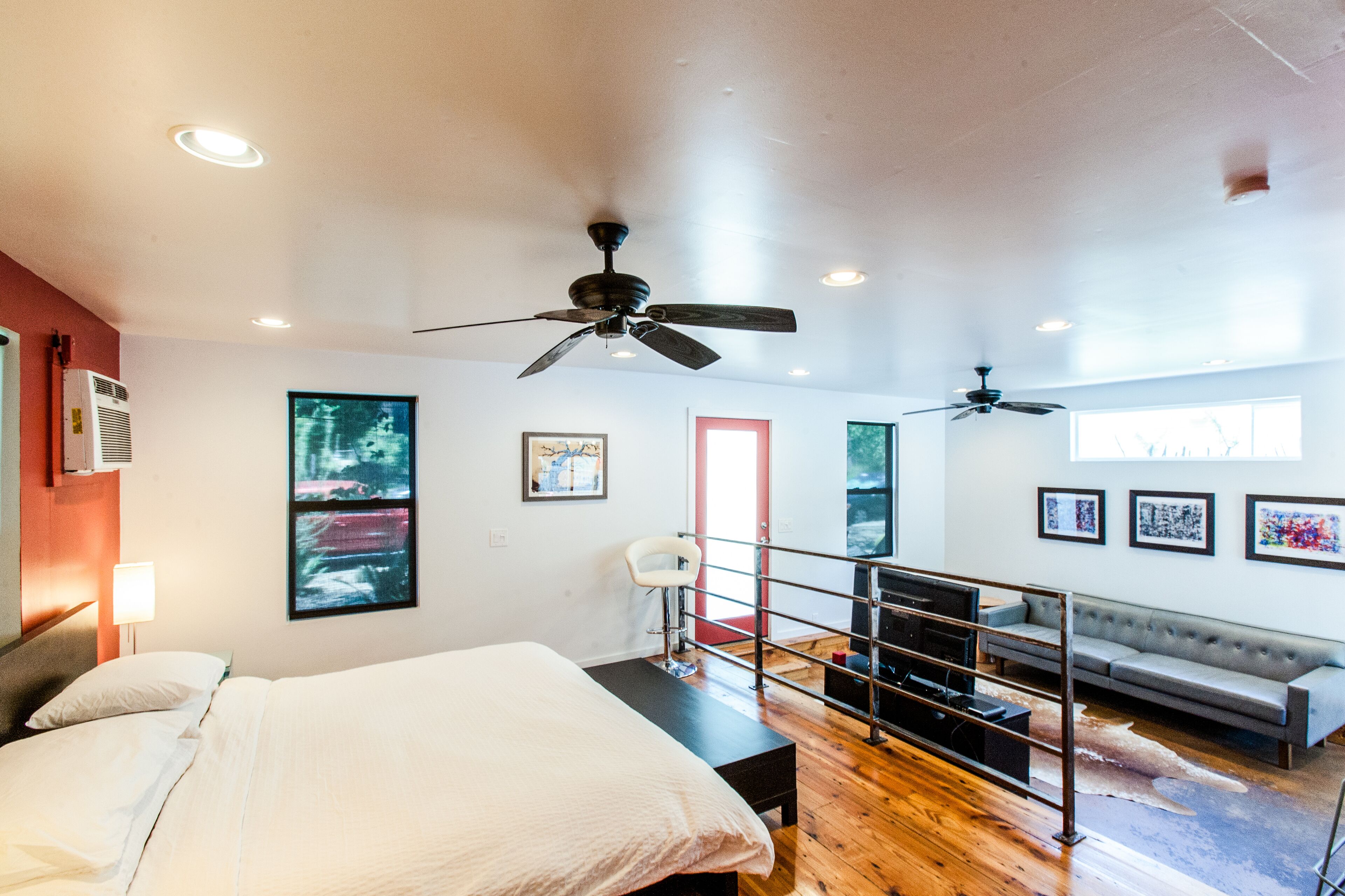 Une chambre d’hôtel moderne avec un grand lit, des ventilateurs de plafond, une télévision et un canapé.