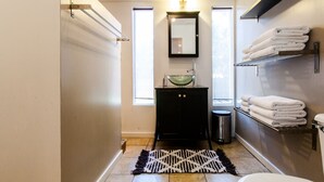 A compact bathroom with a black vanity, a glass sink, a white toilet, and a towel rack.