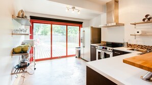 A modern kitchen with a large island, built-in oven, and a sliding glass door leading to an outdoor patio.