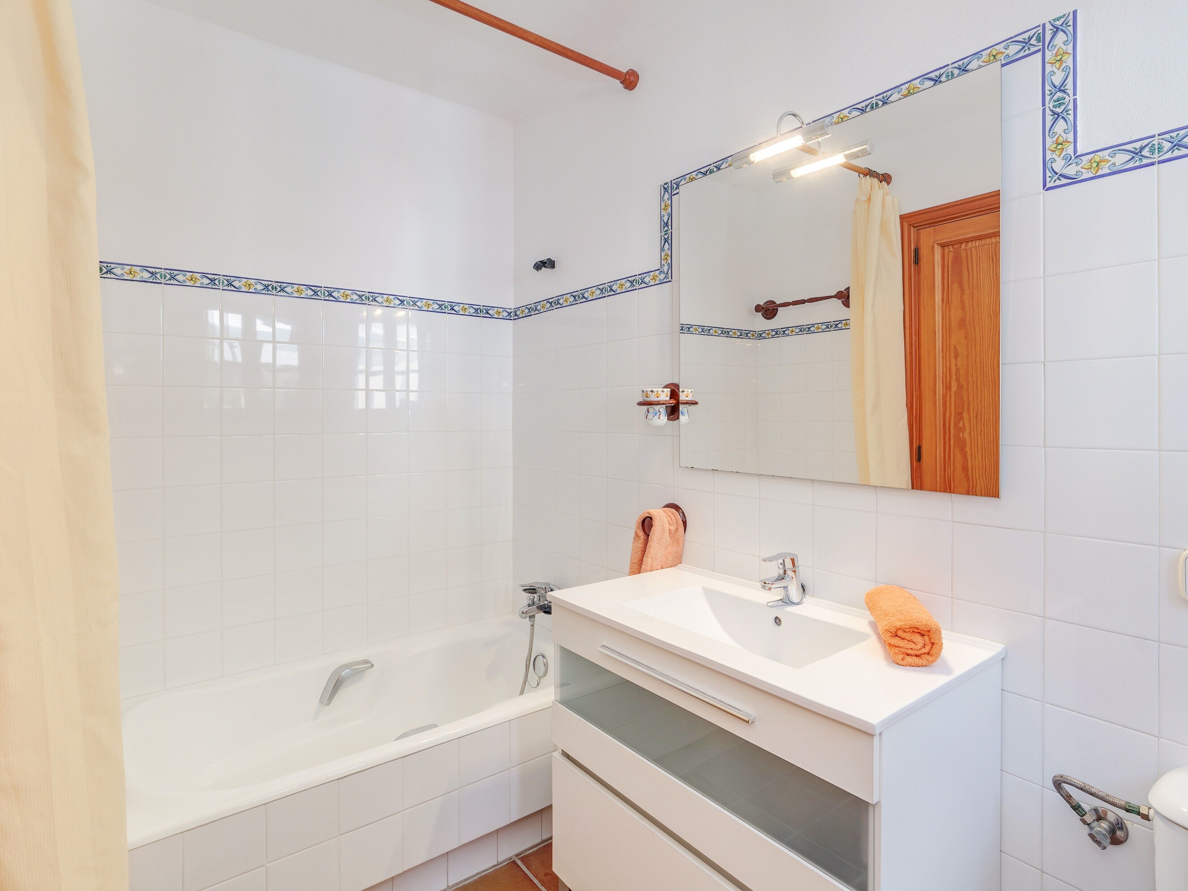 Ein Badezimmer mit einer Badewanne, einem Waschbecken, einem Spiegel und einem Handtuchhalter.
