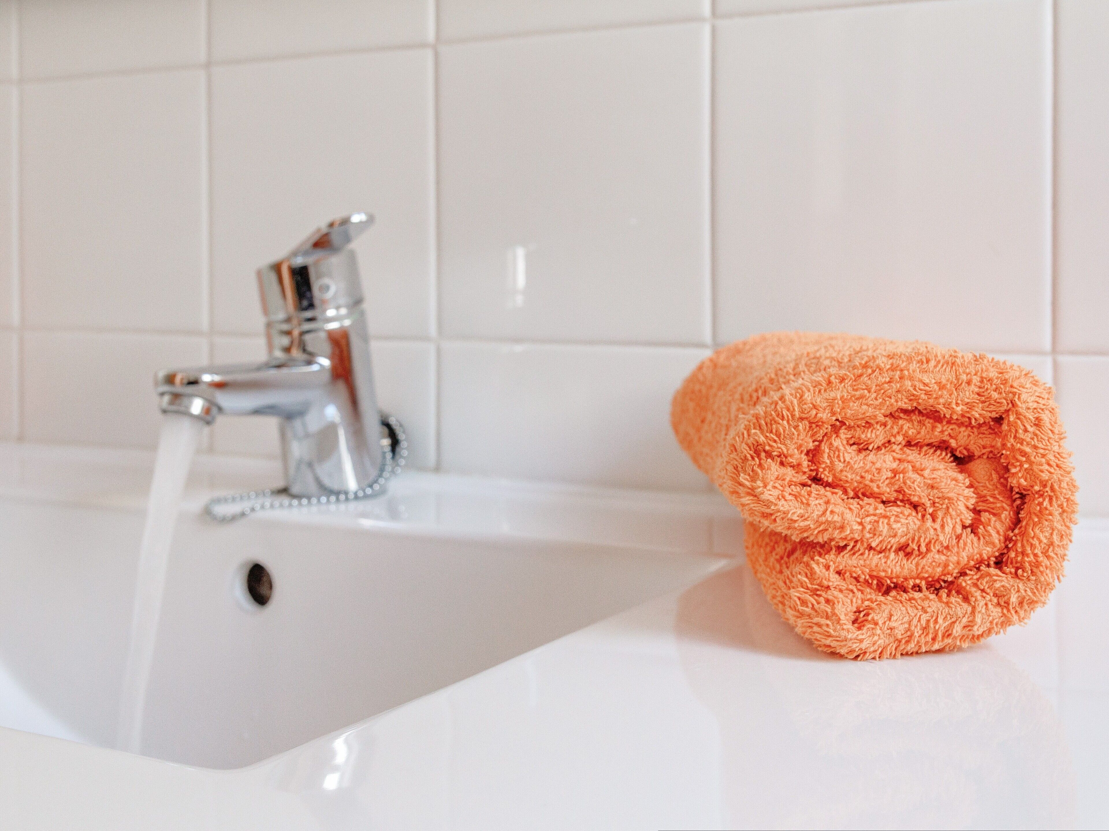 A bathroom sink with a faucet and a rolled-up towel.