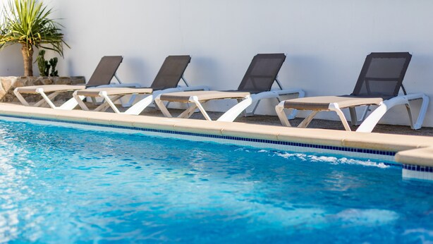 A swimming pool with lounge chairs and a palm tree. - Holiday Home "Villa CA1" with Pool, Garden, Terrace and Wi-Fi (Conil de la Frontera)