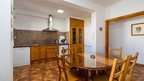 A compact kitchen with a dining area, including a microwave, oven, and wooden cabinets. - Holiday Home "Villa CA1" with Pool, Garden, Terrace and Wi-Fi (Conil de la Frontera)