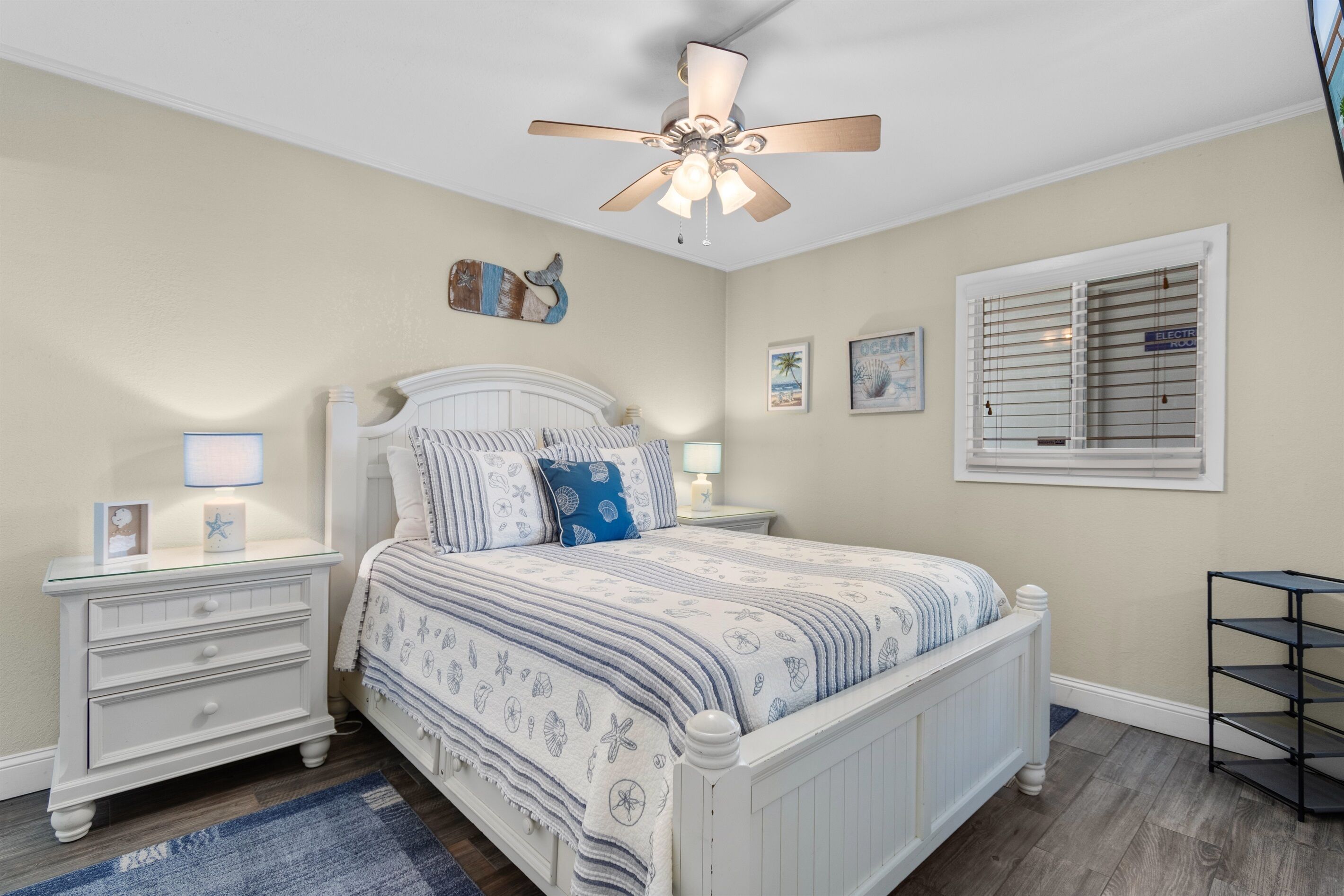 A bedroom with a bed, nightstands, a ceiling fan, and a window with blinds.