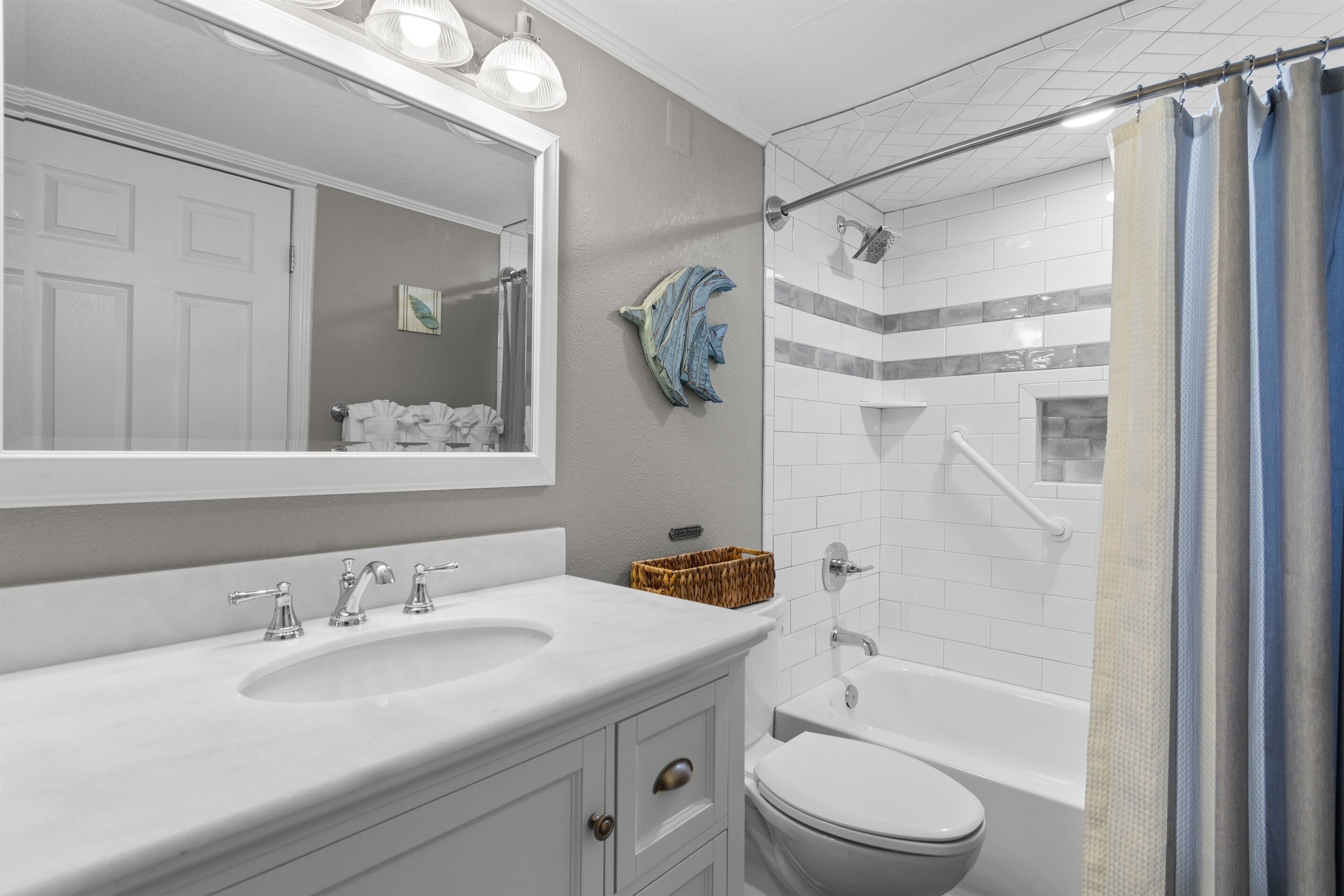 A bathroom with a white sink, mirror, and toilet. There is a shower curtain and a towel rack with towels.